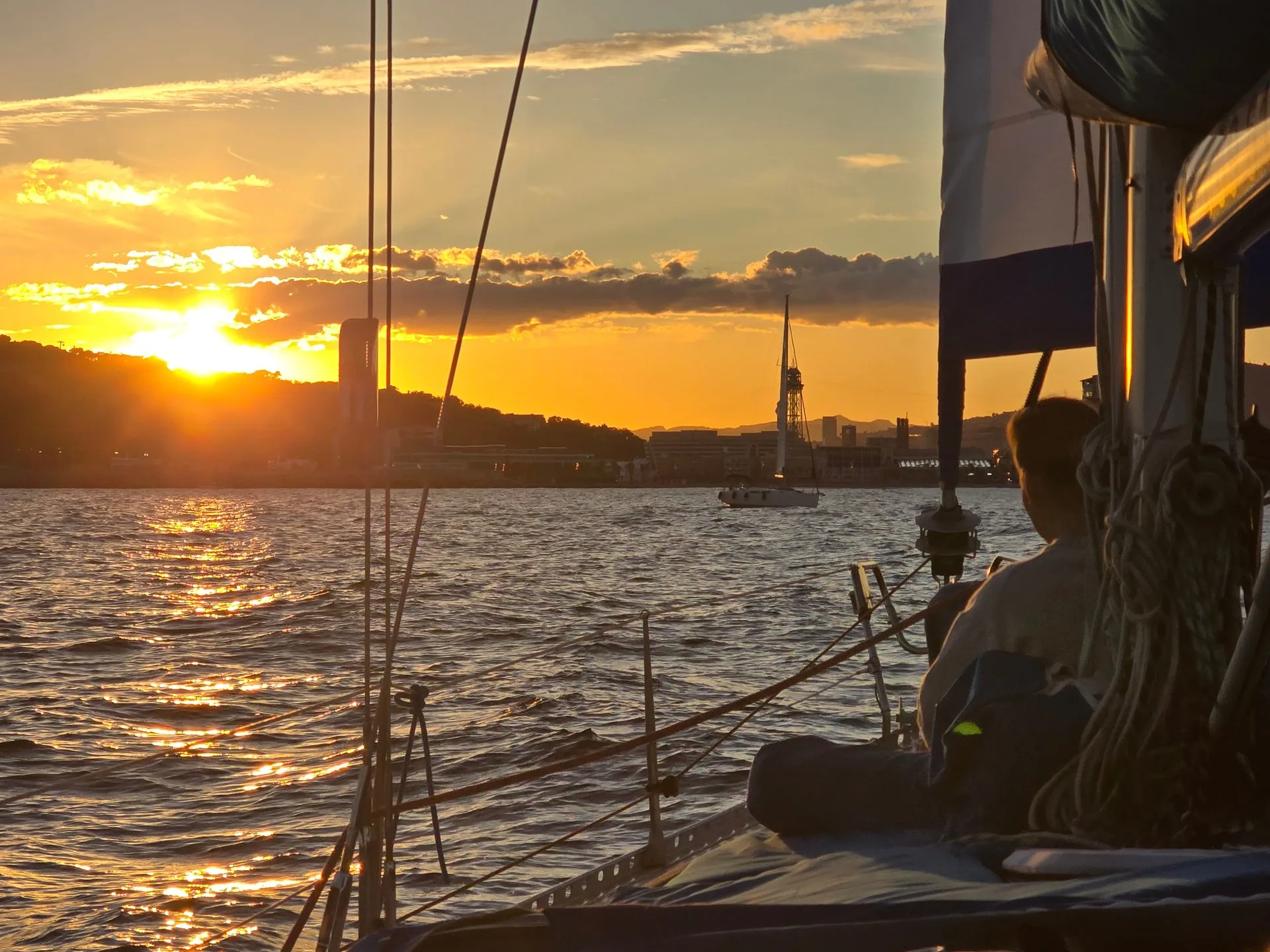 Golden hour sunset from sailboat with Barcelona skyline