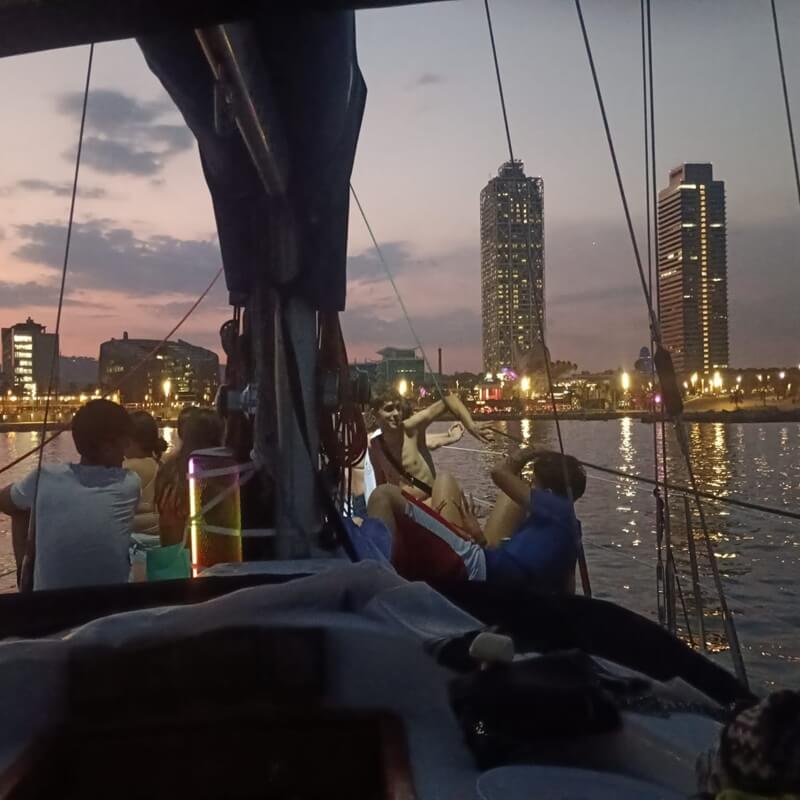 Velero privado al atardecer frente al skyline de Barcelona