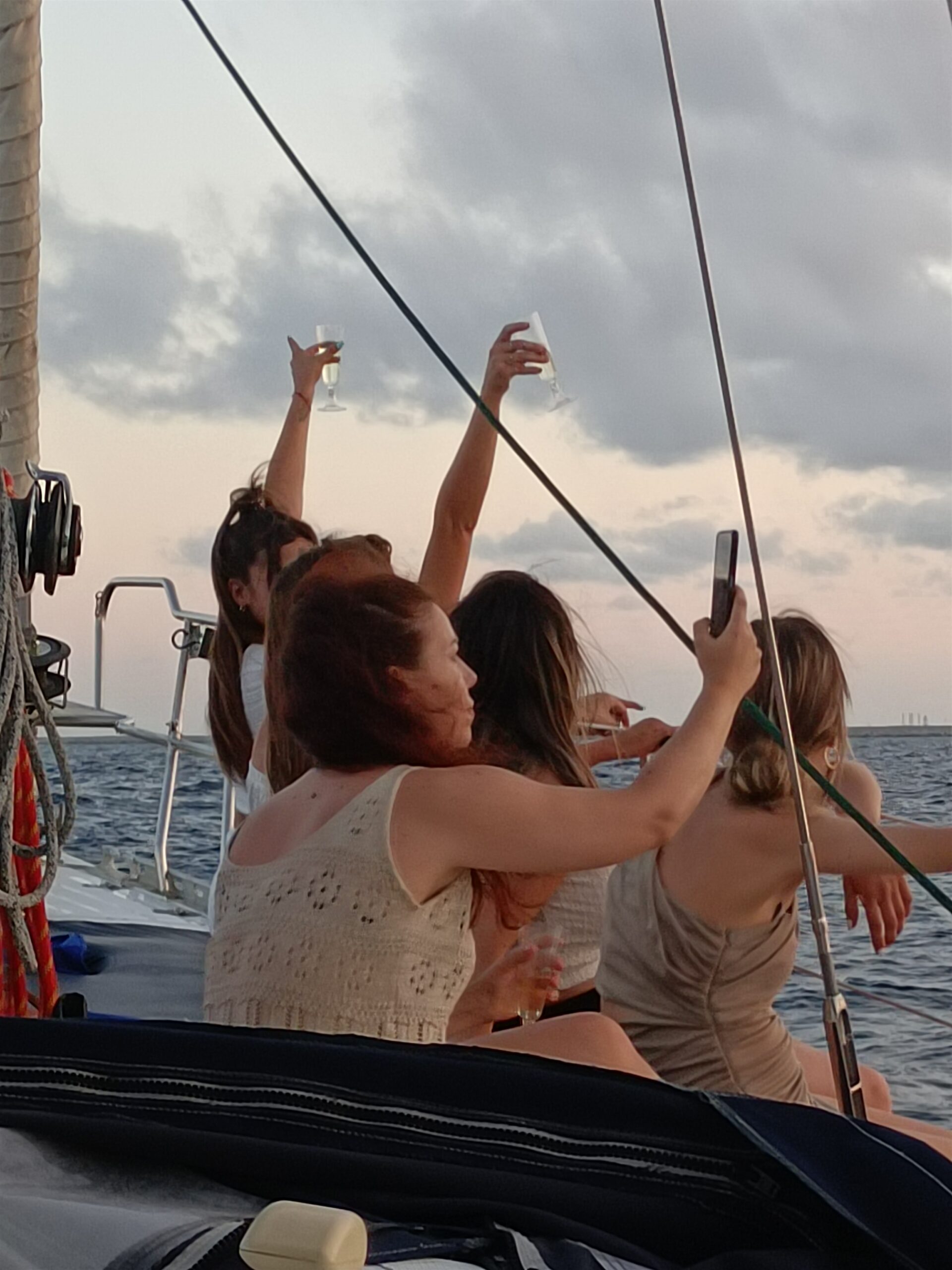 Pasajeras brindando al atardecer a bordo del velero privado en Barcelona